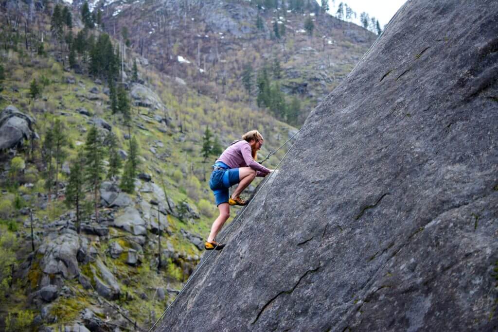Homem se arriscando ao escalar montanha
