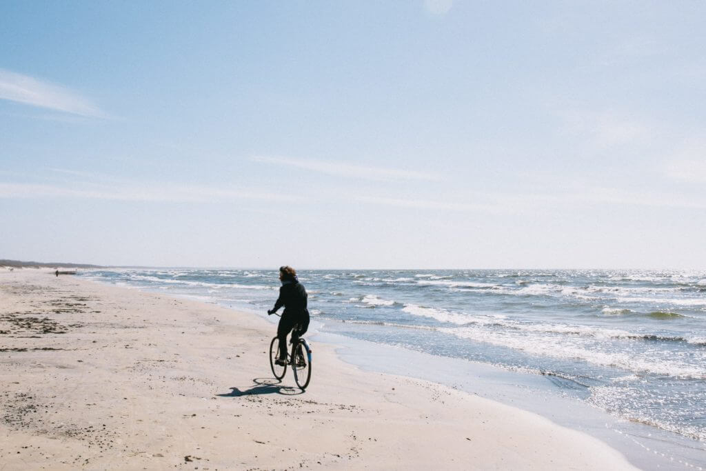 Homem andando de bicicleta sozinho na praia