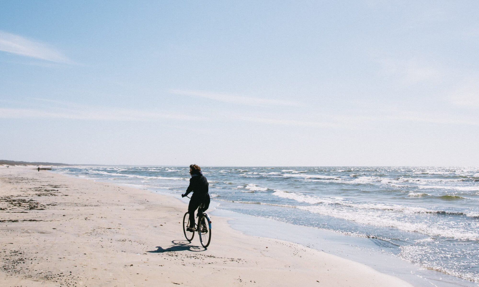 Homem andando de bicicleta sozinho na praia